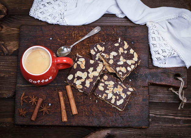 Caffè con schiuma in una tazza di ceramica rossa sul tagliere della cucina