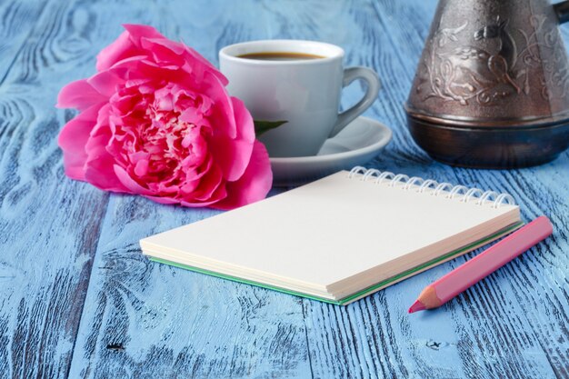 Caffè con taccuino e fiore di peonia