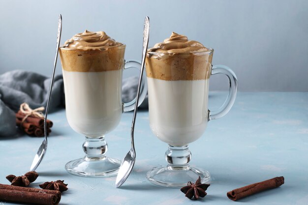 Caffè cremoso Dalgona in due bicchieri su fondo azzurro con schiuma montata. Tendenza del caffè coreano