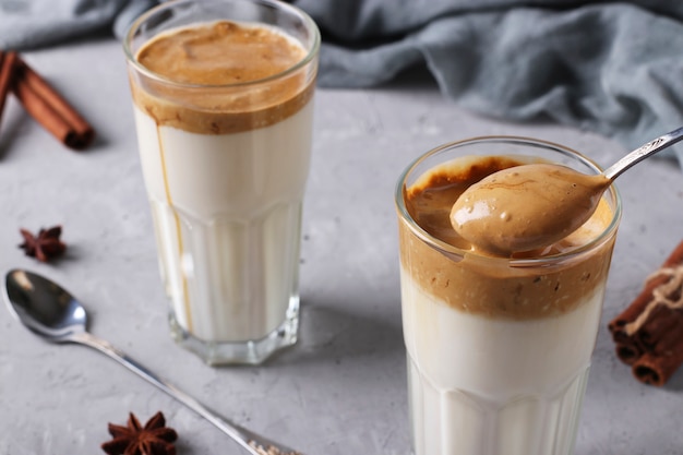 Caffè cremoso Dalgona in un bicchiere su fondo grigio chiaro con schiuma montata