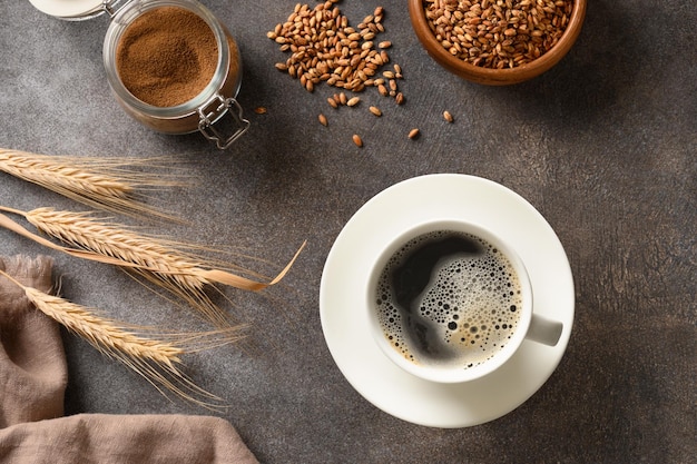 Caffè d'orzo in tazza bianca e spighe d'orzo su sfondo marrone