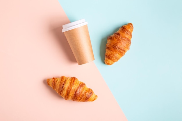 Caffè da asporto in una tazza di carta con croissant, vista dall'alto.