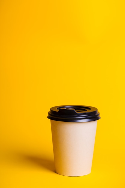 Caffè da portar via. tazza di carta con caffè su uno sfondo giallo.