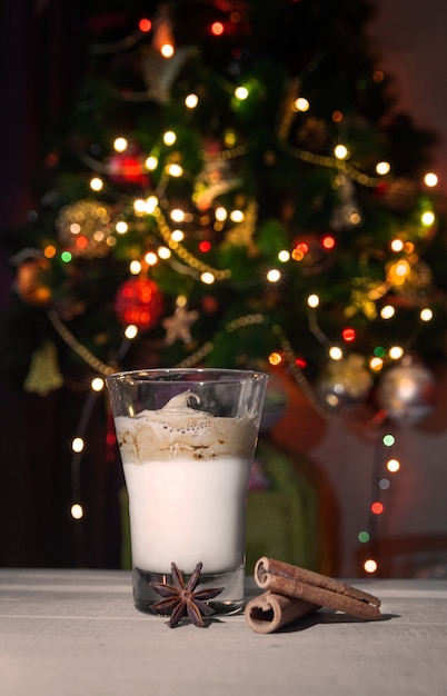 Caffè Dalgona in un bicchiere trasparente su un tavolo di legno sullo sfondo di un albero di Natale