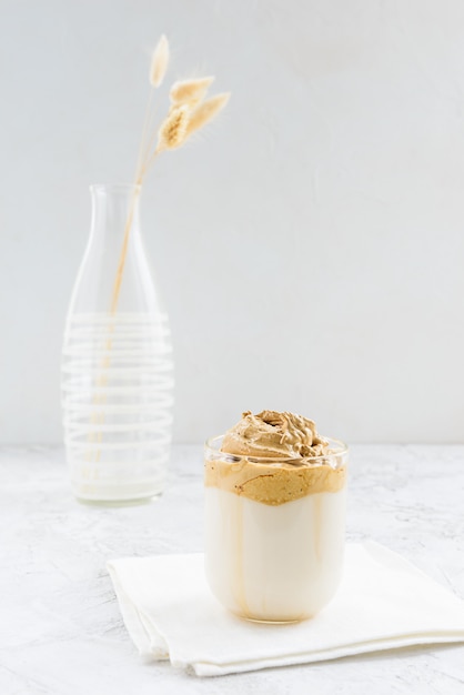 Caffè Dalgona in una tazza di vetro su un tovagliolo bianco.