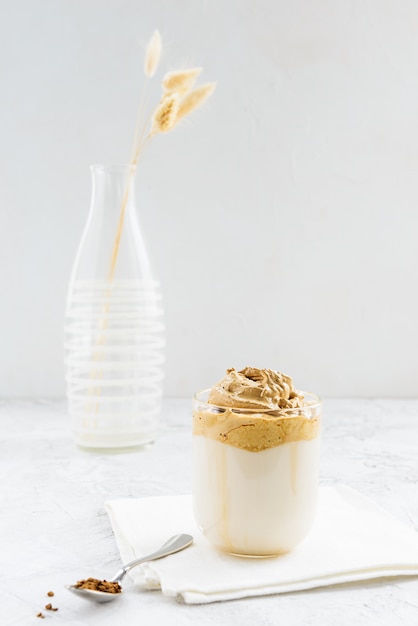 Caffè dalgona panna montata in una tazza di vetro su un tovagliolo bianco.