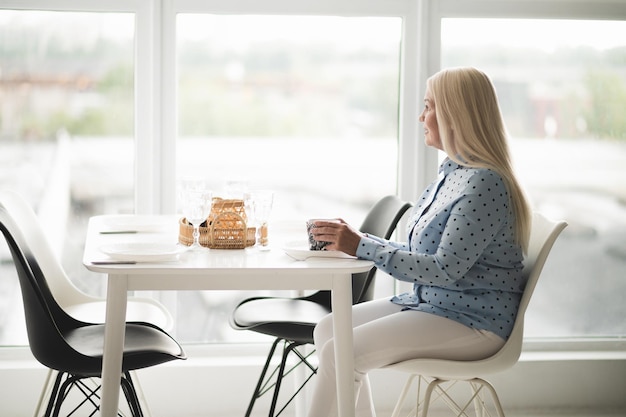 Caffè del mattino. Bionda donna di mezza età che ha il suo caffè mattutino