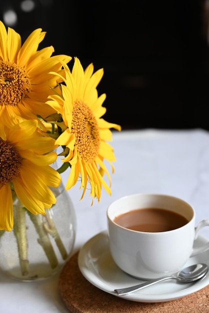 Caffè del mattino Composizione accogliente una tazza di caffè su un libro aperto un maglione blu e fiori di girasole su uno sfondo concreto Concetto di natura morta Copia spazio