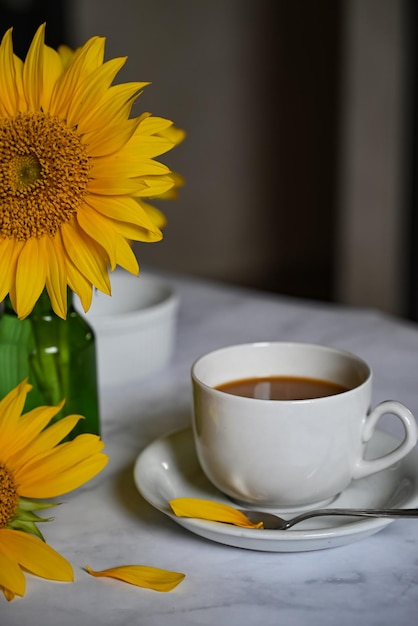 Caffè del mattino Composizione accogliente una tazza di caffè su un libro aperto un maglione blu e fiori di girasole su uno sfondo concreto Concetto di natura morta Copia spazio