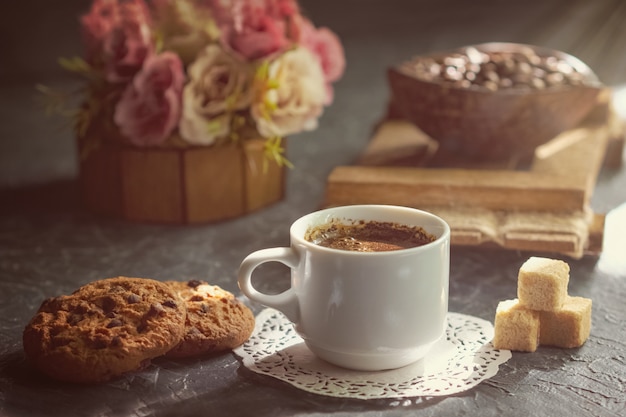 Caffè del mattino con biscotti e pezzi di zucchero di canna in raggio di sole.