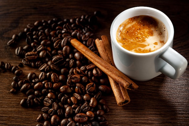 Caffè del mattino Tazza di caffè cannella e chicchi di caffè su sfondo di legno Vista dall'alto