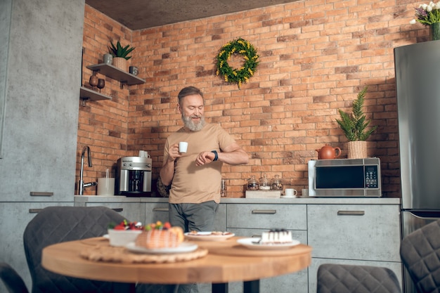 Caffè del mattino. Un uomo di mezza età in piedi in cucina con una tazza di caffè in mano