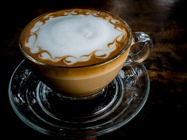 Caffè di arte del latte di vista laterale sulla tavola di legno, scuro