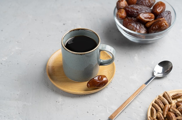 Caffè di semi di dattero sano in tazza piccola datteri frutti e semi su fondo di cemento grigio cucchiaino da tè