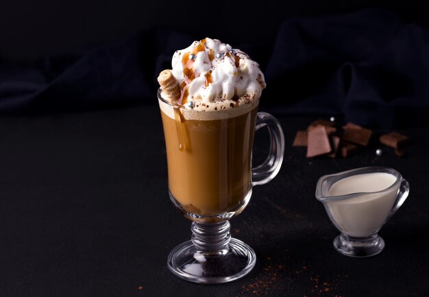 Caffè dolce con caramello e panna su sfondo nero