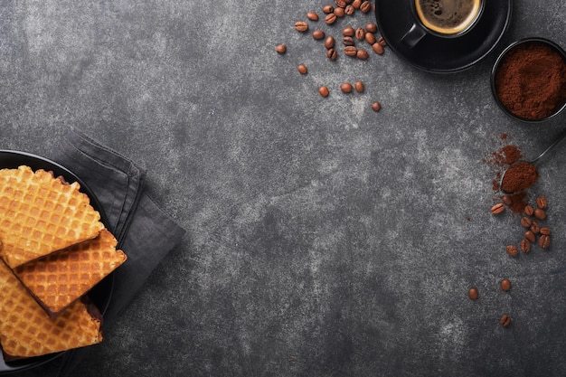 Caffè e cialde olandesi Caffè espresso e cialde olandesi o biscotti con cialde sciroppo con cioccolato su vecchio tavolo di cemento nero Biscotti perfetti con cialde sciroppo per colazione Vista dall'alto Mock up