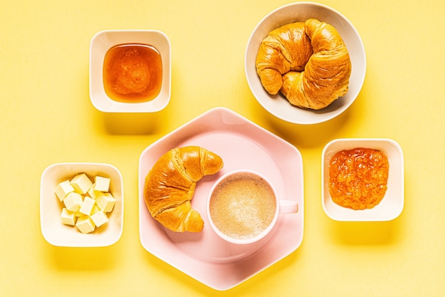 Caffè e croissant per colazione su uno sfondo giallo, vista dall'alto,