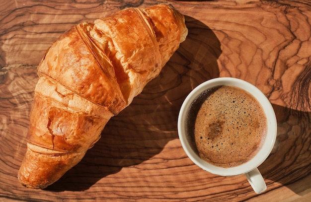 Caffè e croissant su tavola di legno colazione francese idea giornata soleggiata e luminosa Vista dall'alto piatto con spazio per la copia del testo