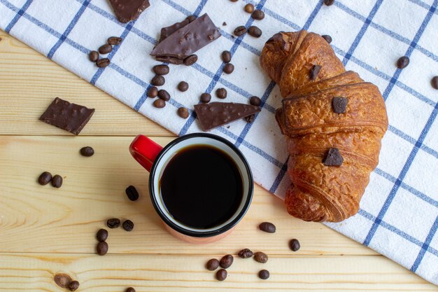 Caffè e croissant su uno sfondo di legno. La vista dall'alto. Chicco di caffe