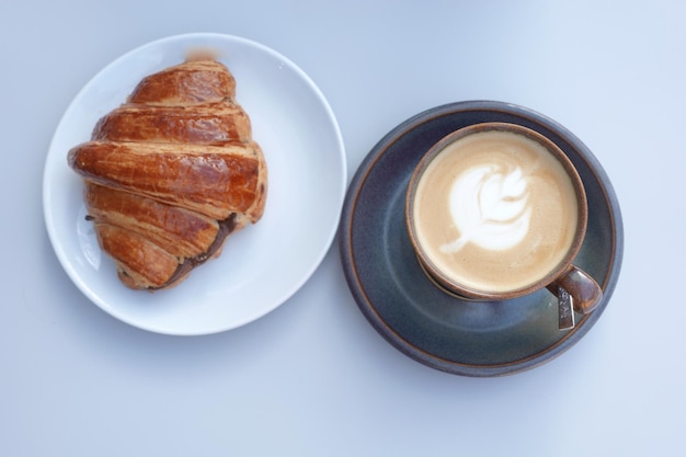 Caffè e croissant sulla vista del piano d'appoggio in legno