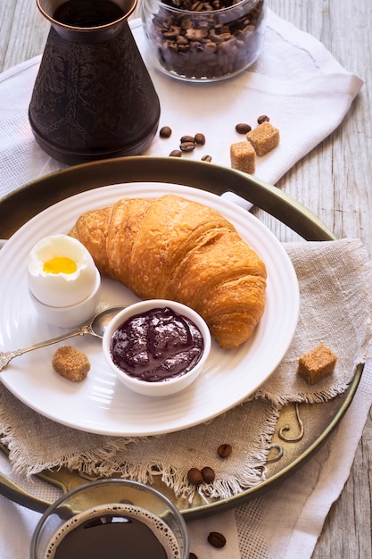 Caffè e croissant, uova e marmellata per colazione