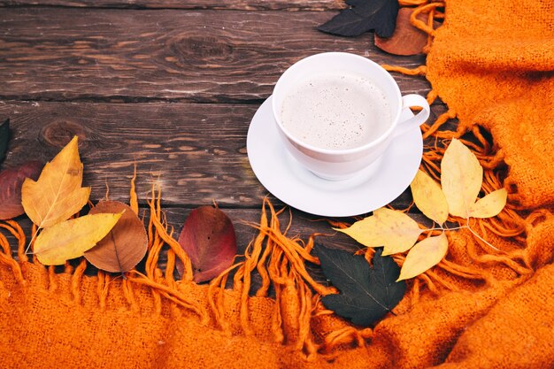 caffè e foglie autunnali su fondo in legno