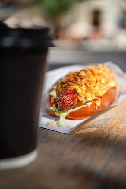 Caffè e salse saporiti degli hot dog su fondo di legno