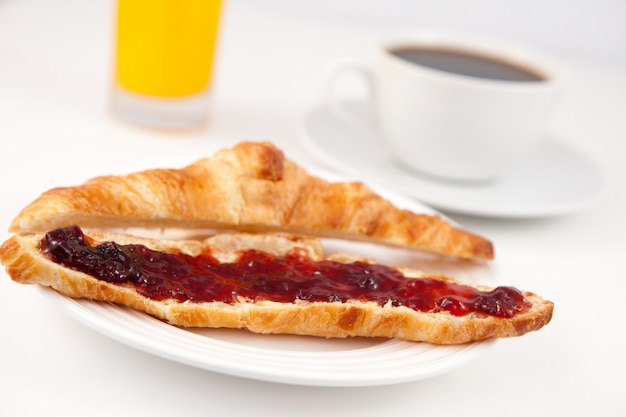 Caffè e succo d&#39;arancia dietro un croissant