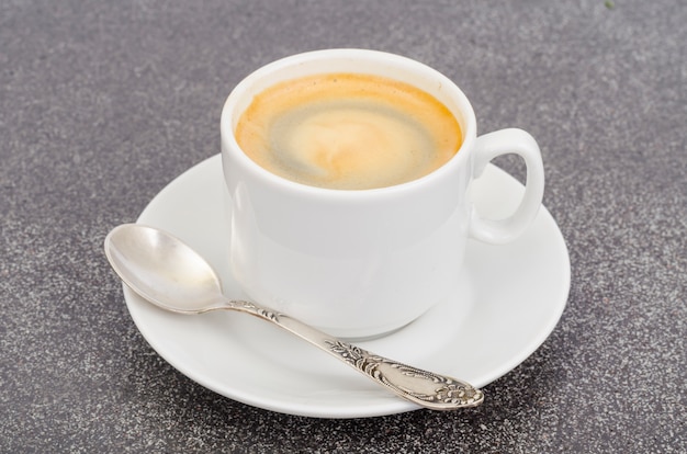 Caffè espresso bianco della tazza con schiuma su pietra grigia