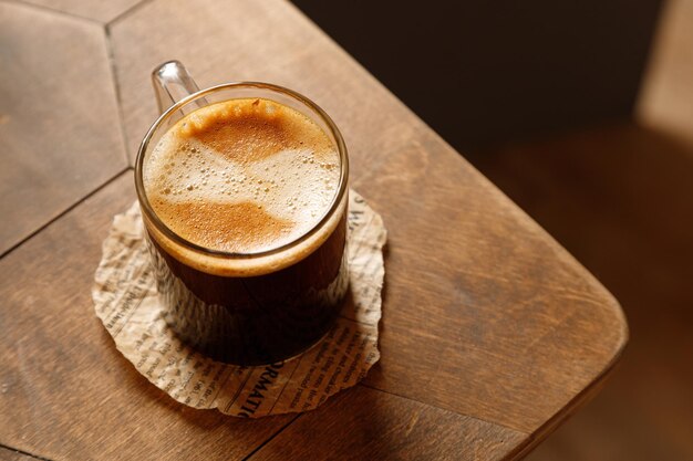 Caffè espresso in una tazza di vetro con cheesecake su fondo di legno