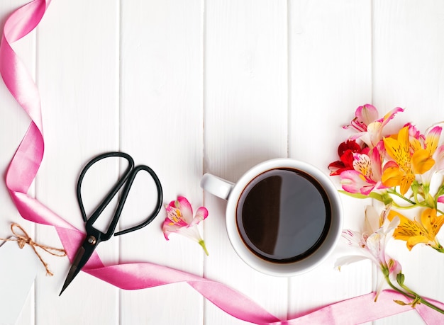 Caffè, fiori e forbici sulla tavola di legno bianca