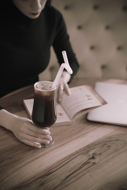 Caffè freddo con latte. Latte freddo al caffè. Donna che tiene una tazza di caffè freddo in vetro.