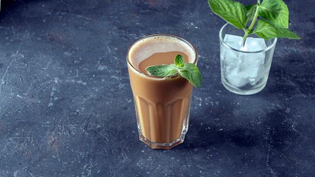 Caffè freddo con menta e latte. Grande bicchiere di cocktail al caffè e bicchiere con cubetti di ghiaccio