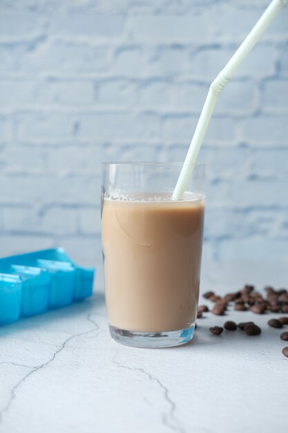 Caffè freddo in un bicchiere alto con chicchi di caffè sul tavolo