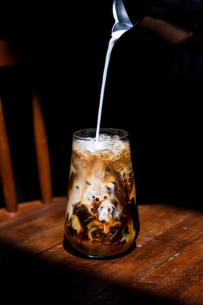 Caffè freddo su un tavolo di legno con panna versata al suo interno che mostra la consistenza e l'aspetto rinfrescante