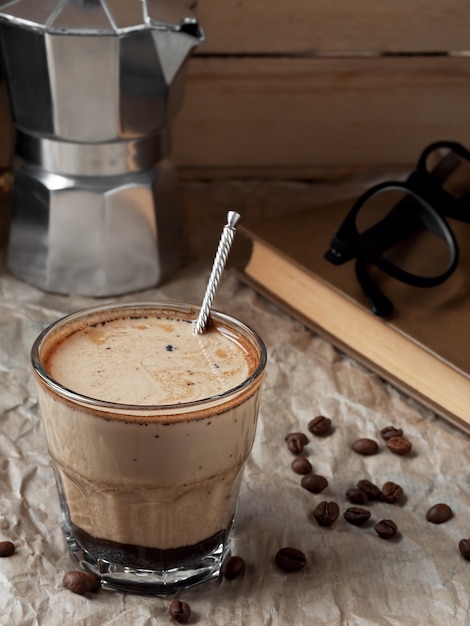 Caffè fresco in un bicchiere con panna e chicchi di caffè