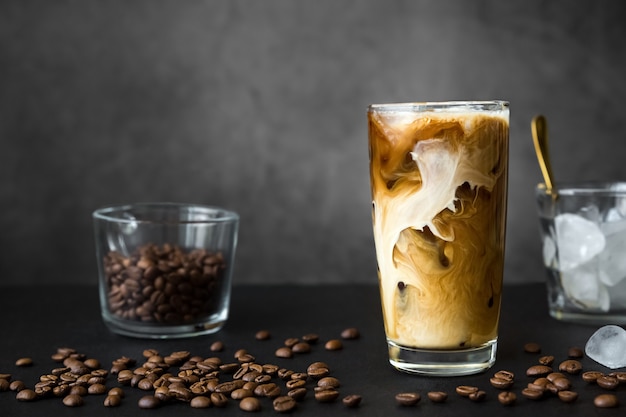 Caffè ghiacciato in bicchiere alto con contenitore per crema con chicchi di caffè ghiacciato