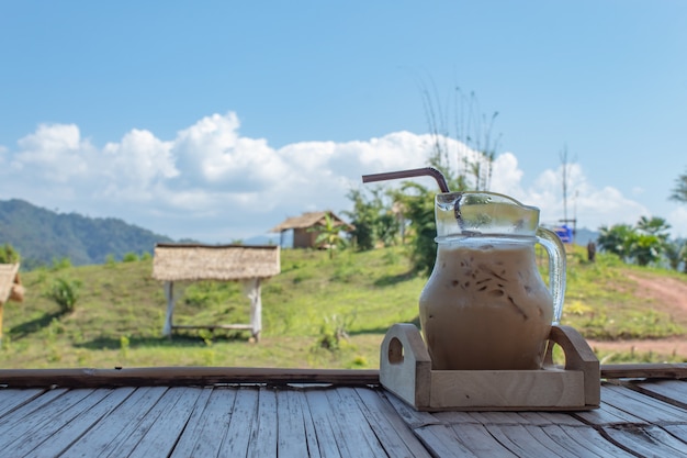 Caffè ghiacciato in un barattolo di vetro e vista casa in legno sulla montagna.