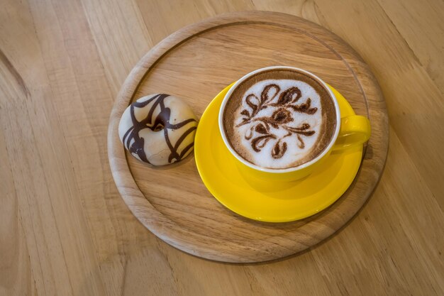 Caffè in tazza gialla sulla tavola di legno