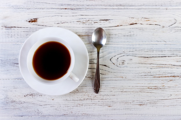 Caffè in una tazza con il cucchiaio su una priorità bassa bianca