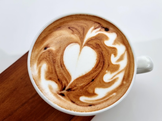 Caffè laterale del negozio una tazza di caffè caldo di arte del latte sul piatto di legno