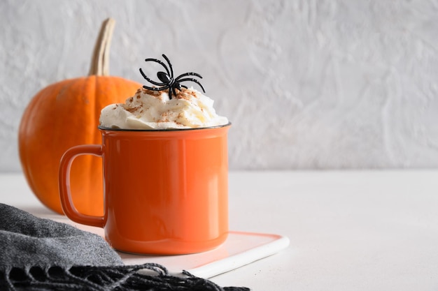 Caffè latte alla zucca di Halloween con ragni decorati con panna montata