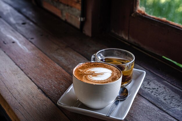 Caffè latte caldo con latte art schiuma di latte in tazza tazza tè caldo sulla scrivania di legno vista dall'alto Come colazione In un caffè Negozio in stile vintage al bar durante il concetto di lavoro aziendale