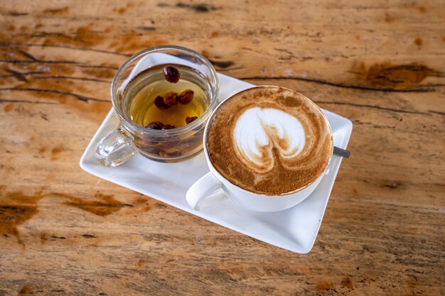 Caffè latte caldo con latte art schiuma di latte in tazza tazza tè caldo sulla scrivania di legno vista dall'alto Come colazione In un caffè Negozio in stile vintage al bar durante il concetto di lavoro aziendale