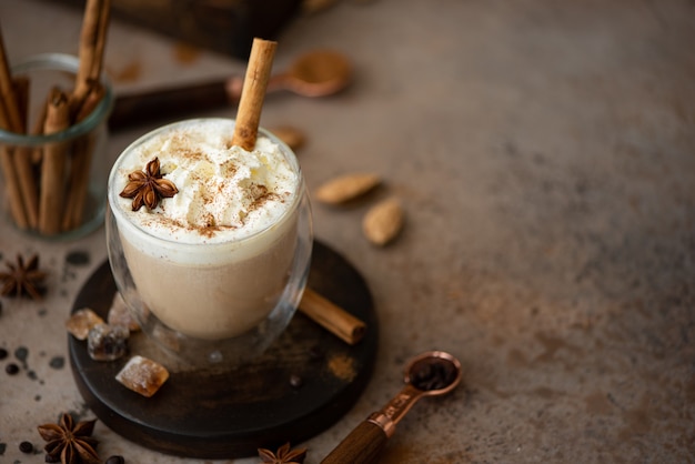 Caffe latte con panna montata, cannella e anice in un bicchiere