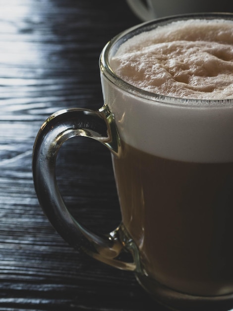 Caffè latte sul tavolo di legno nero vicino alla finestra Pausa caffè