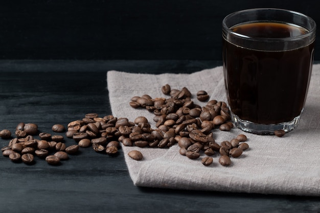 Caffè nero con il suo grano, fuoco selettivo.