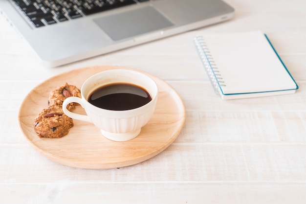 caffè nero e biscotti con laptop e taccuino