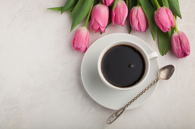 Caffè nero in tazza bianca e tulipani.