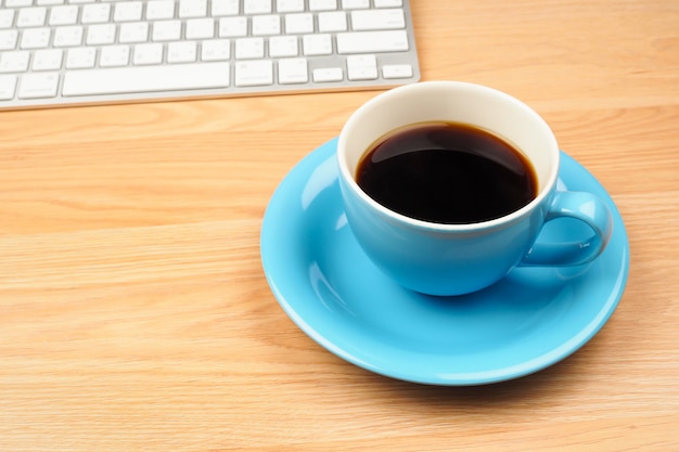 Caffè nero in tazza blu sul fondo di legno marrone della tavola